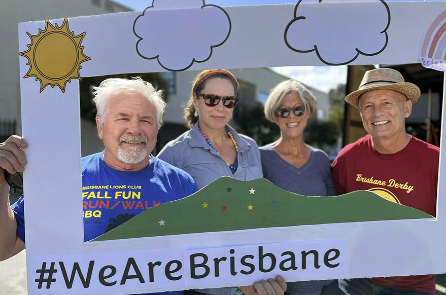 group of older adults holding a cardboard frame with the words #WeAreBrisbane on it.