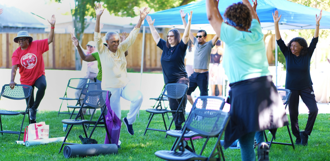 group of older adults exercising outside, on a grassy patch.